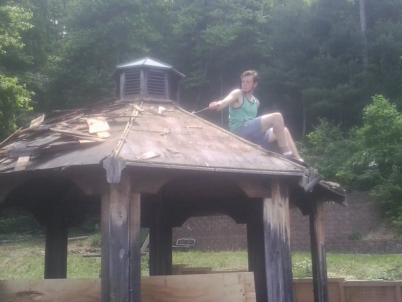 Tearing the old roof off a wooden gazebo before new shakes in Cambridge
